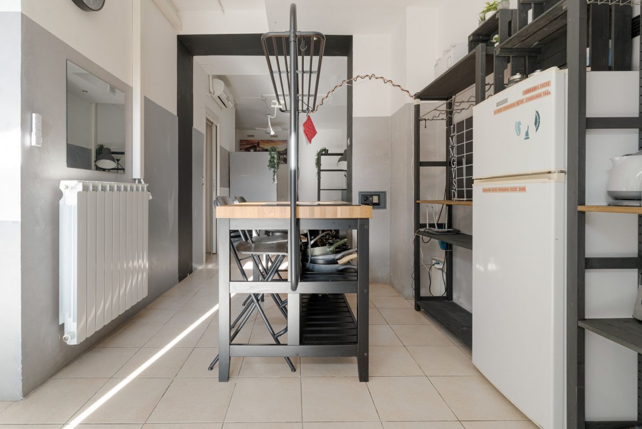 Een keuken met een centraal eiland, een koelkast en een radiator.