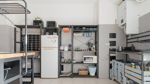Eine Küche mit Metallregalen, einem Kühlschrank und verschiedenen Küchengeräten.