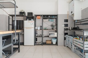 A kitchen with metal shelving, a refrigerator, and various kitchen appliances. - Modern 49m2 loft, ideal for 4 people, located in the basement of a building (steps to access).The accommodation is located in the Navigli area, one of the most picturesque areas of the city, with its historic canals and the center of Milanese nightlife.A (Milan)
