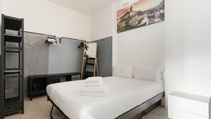 Ein Schlafzimmer mit Bett, Schreibtisch, Stuhl, Kleiderschrank und einem Bild an der Wand.