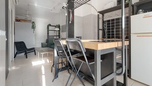 Eine moderne Küche mit Holzarbeitsplatte, Metallstühlen, einer Kleiderstange und einem Kühlschrank.