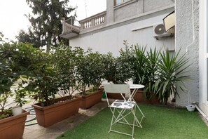 A small patio area with a white folding chair, a table, and several potted plants. - Modern 49m2 loft, ideal for 4 people, located in the basement of a building (steps to access).The accommodation is located in the Navigli area, one of the most picturesque areas of the city, with its historic canals and the center of Milanese nightlife.A (Milan)