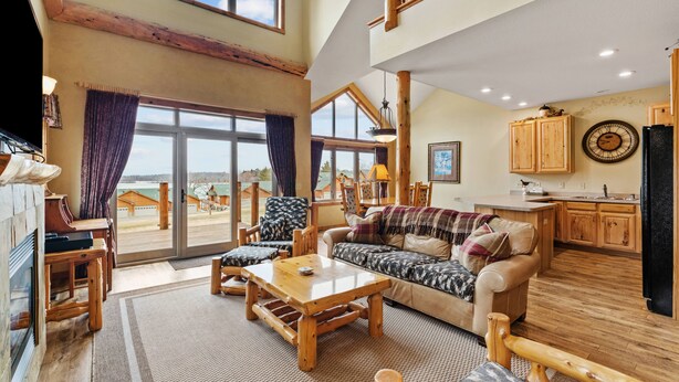 Amplia sala de estar con un gran ventanal, muebles de madera y una zona de cocina.