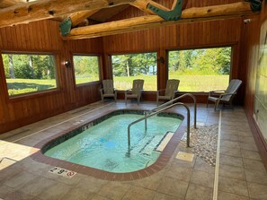 Un espace piscine doté d’un jacuzzi, de murs en bois et offrant une vue sur l’extérieur.