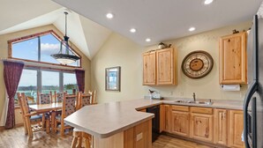 Una cocina con armarios de madera, un ventanal grande y un comedor con sillas.