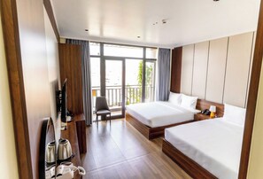 Quarto de hotel com duas camas, área de estar, televisão e varanda com vista.