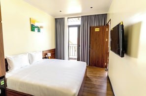 Quarto de hotel com uma cama grande, televisão fixada na parede e porta com o número 505.