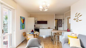 A compact living space with a dining area, kitchenette, and a sofa with cushions. - Sirio Vista Blu Apartment by Interhome (San Lorenzo al Mare)