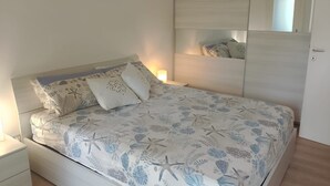 A bed with a floral and starfish pattern, a bedside lamp, a nightstand, and a mirror on the wall. - Family-friendly villa for eight guests (Bibione)