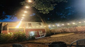 Una casa con porche, luces colgantes y un árbol.