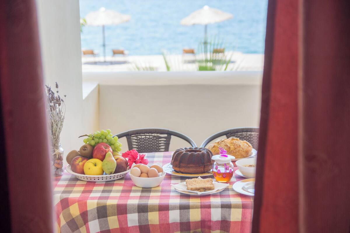 A table with fruits, eggs, a cake, and a honey jar, overlooking a pool area.