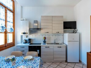 Eine moderne Küche mit Esstisch für vier Personen, Backofen und Kühlschrank.