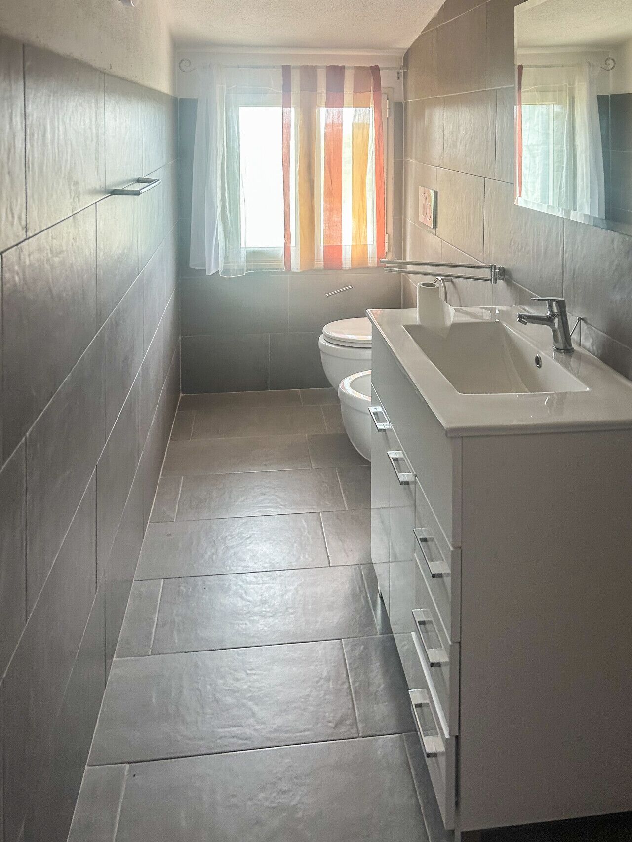Une salle de bain moderne équipée de toilettes, d’un lavabo et d’un miroir.