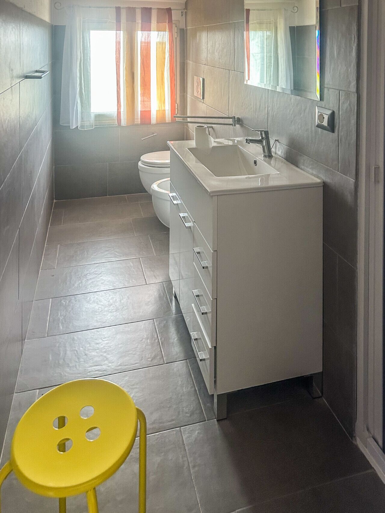 A bathroom with a toilet, sink, and mirror.