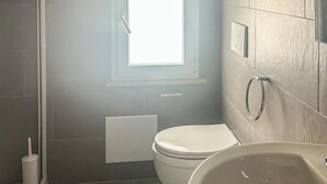 Un baño con inodoro, lavabo y ventana.