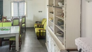 Un comedor con una mesa, sillas y un armario con vajilla.