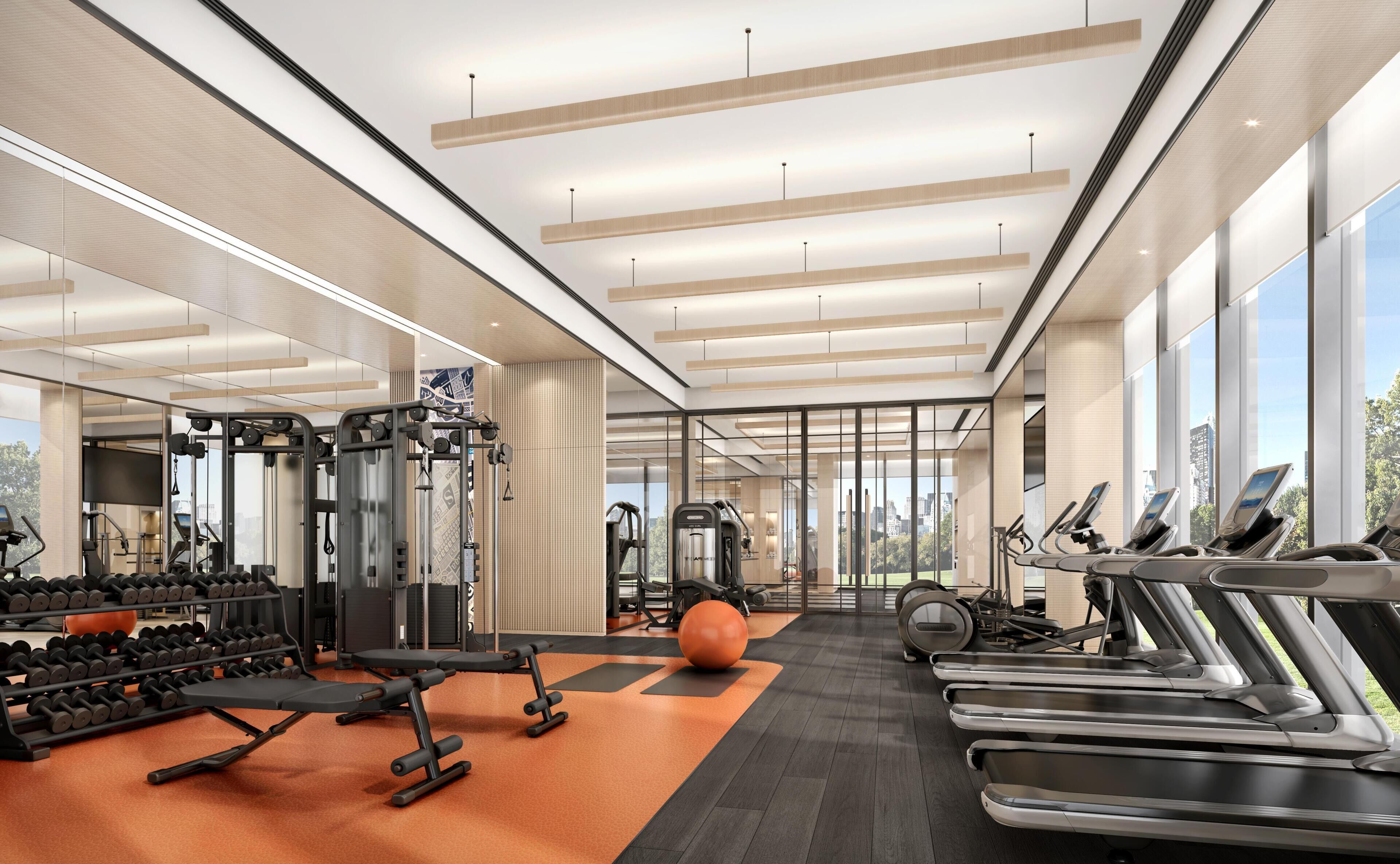 Un gimnasio moderno con equipo de ejercicio, ventanas amplias y vistas a la ciudad.