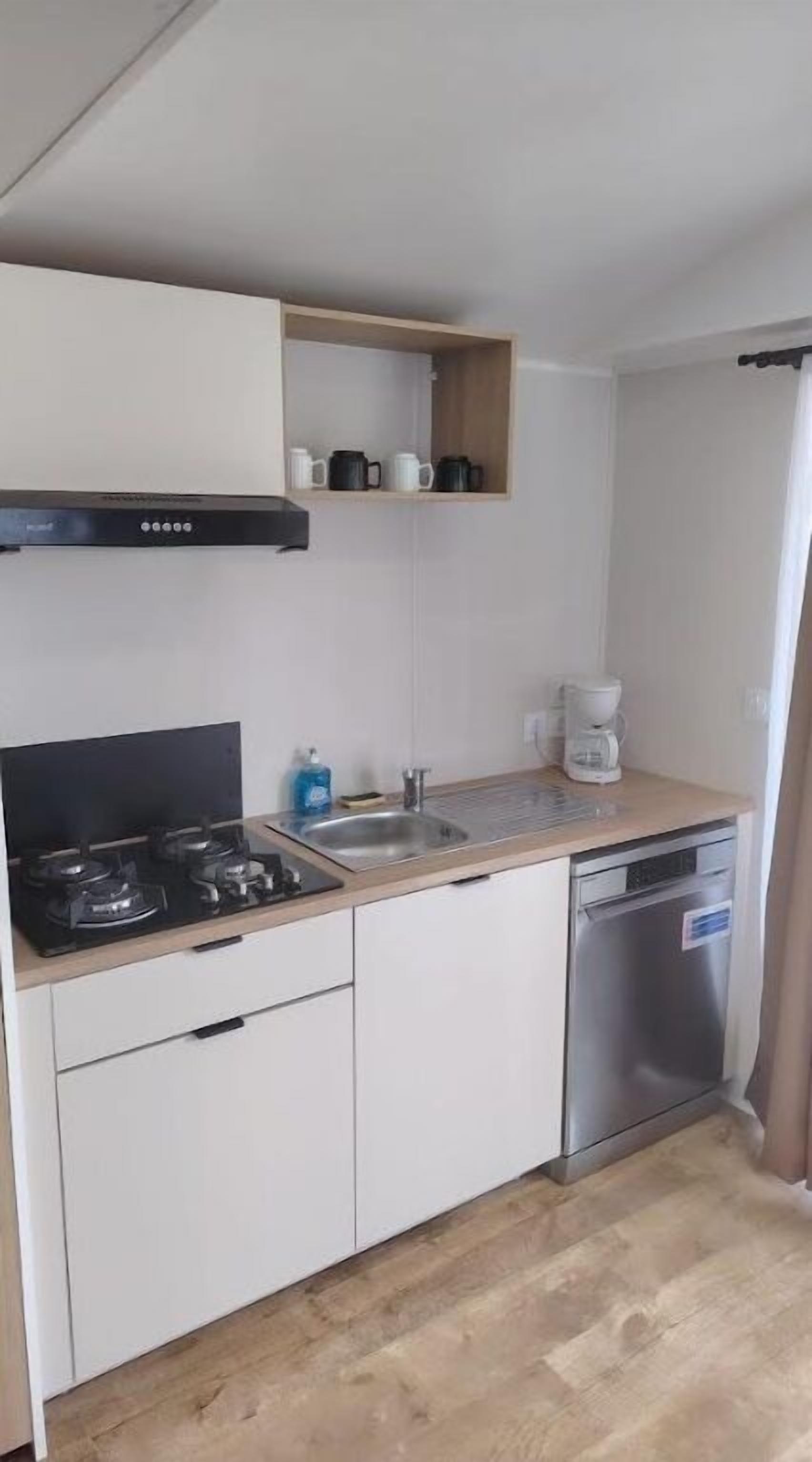 A compact kitchen with a stove, sink, and dishwasher.
