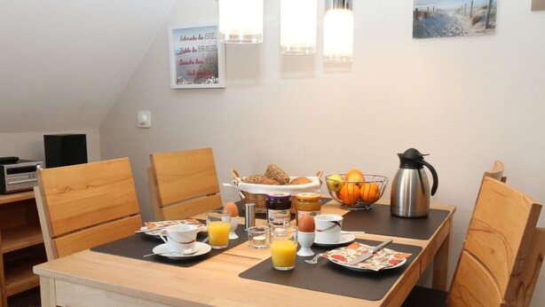A breakfast setup with a table, chairs, and breakfast items including bread, fruit, and a coffee pot. - Vacation apartment Strandaster Zingst, comfortable apartment, close to town and beach (Zingst)