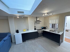 Een moderne keuken met dakraam, inbouwapparatuur en uitzicht op buiten.