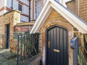 A black door with a brass handle, a stone wall, and a metal gate. - Tower Cottage (Nottingham)