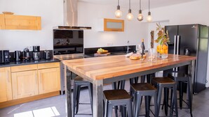 Una cucina moderna con mobili in legno, una grande isola con sgabelli, forno incassato e frigorifero in acciaio inossidabile.