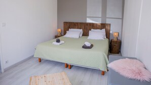 Un letto con una testiera in legno, due comodini con lampade, un piccolo tappeto e un cuscino soffice su un tavolino di fianco al letto.