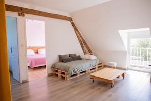 Un dormitori d'estil loft amb un llit, una taula de fusta i vista cap a l'exterior.