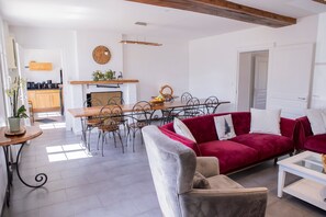 Un saló modern amb un sofà vermell, un butac armchair gris i una zona de menjador amb una taula i cadires de fusta.