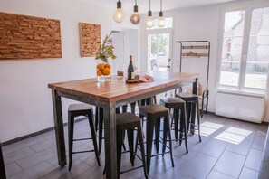 Una cocina con una isla de madera, taburetes de bar, lámparas colgantes y vistas al exterior.