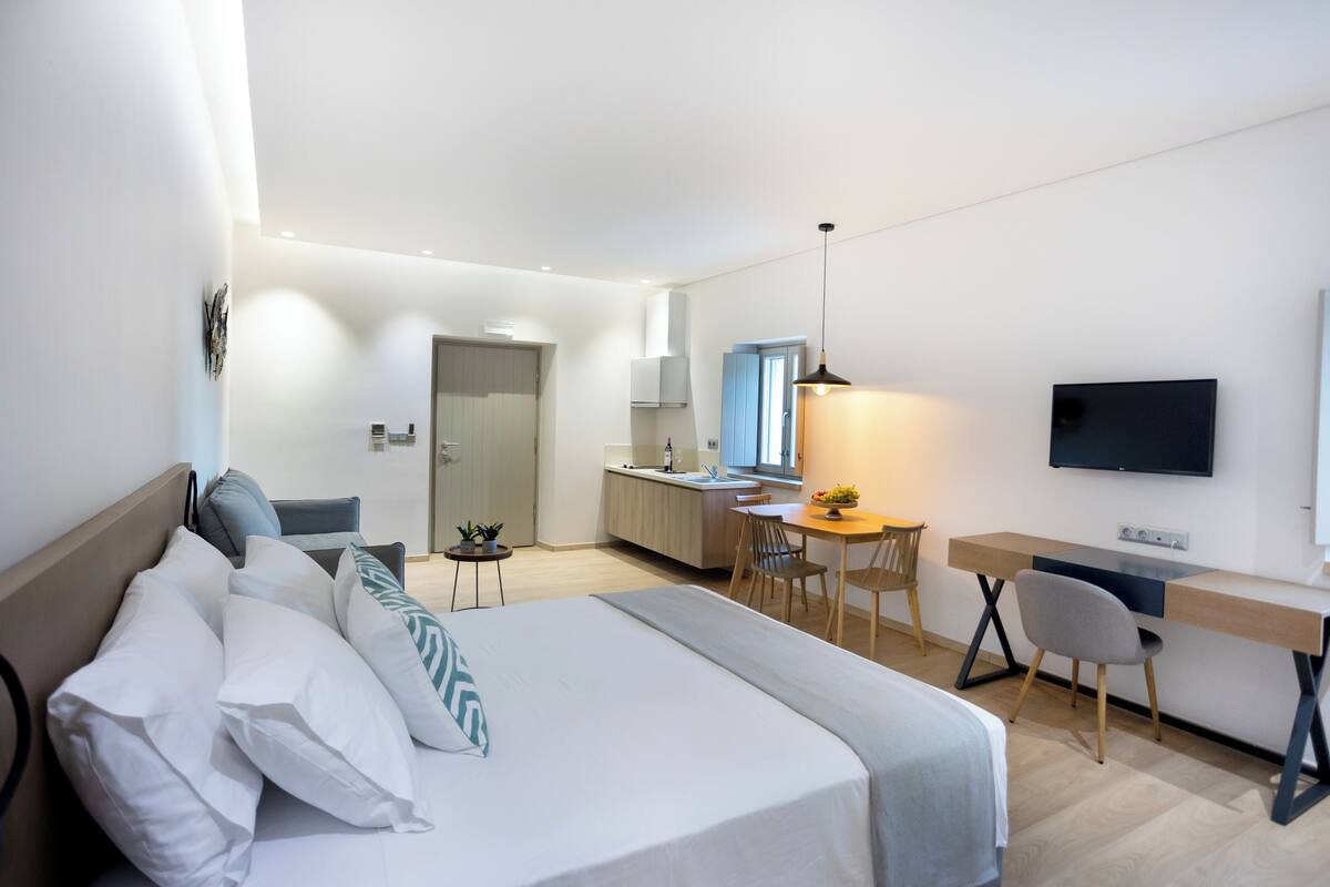 Una habitación de hotel moderna con cama, escritorio, silla y televisor montado en la pared.