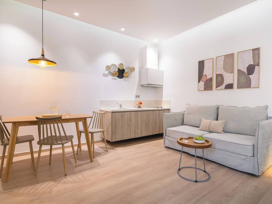 A modern living space with a dining area, kitchenette, and a sofa.