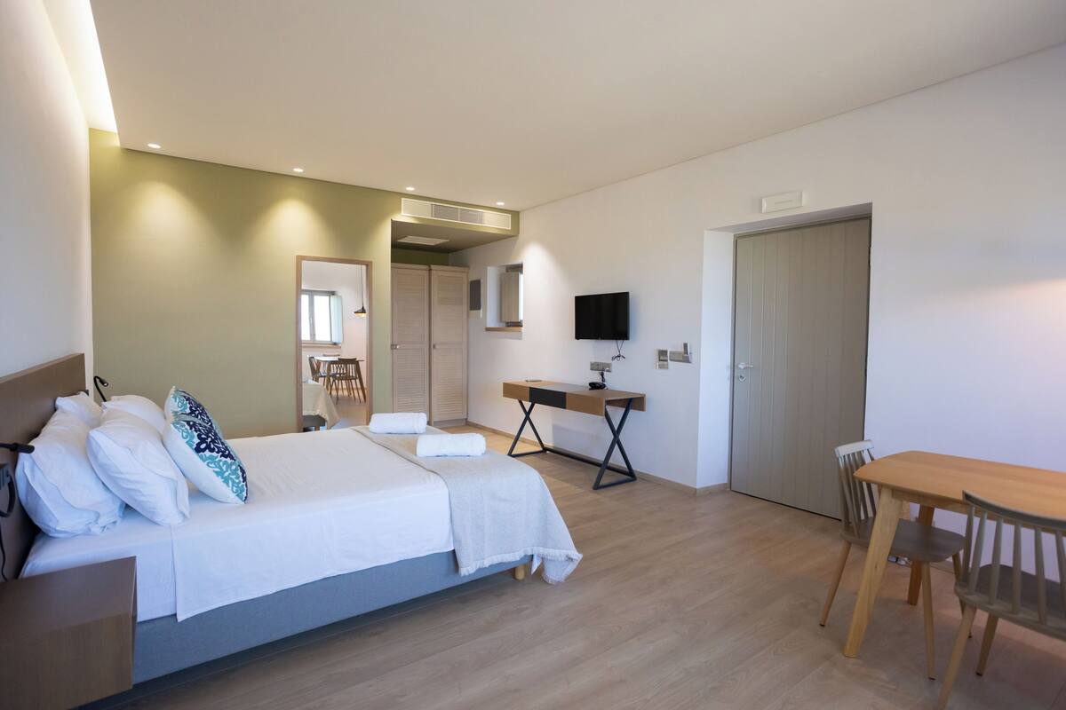 Una habitación de hotel moderna con cama, escritorio, silla y televisor.