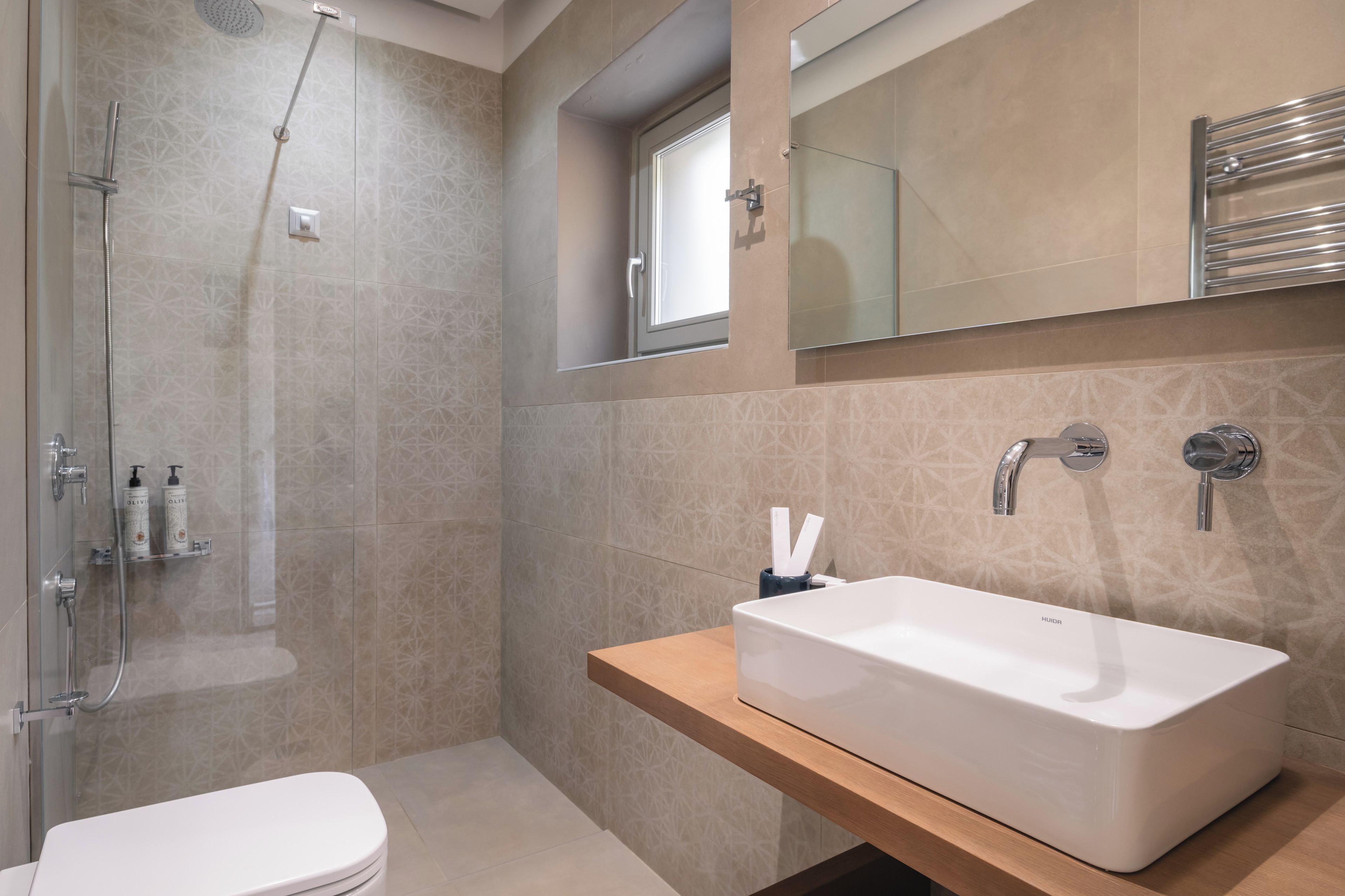 A modern bathroom with a glass-enclosed shower, a white sink, and a mirror above the countertop.