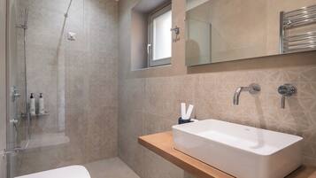 A modern bathroom with a glass-enclosed shower, a white sink, and a mirror above the countertop.