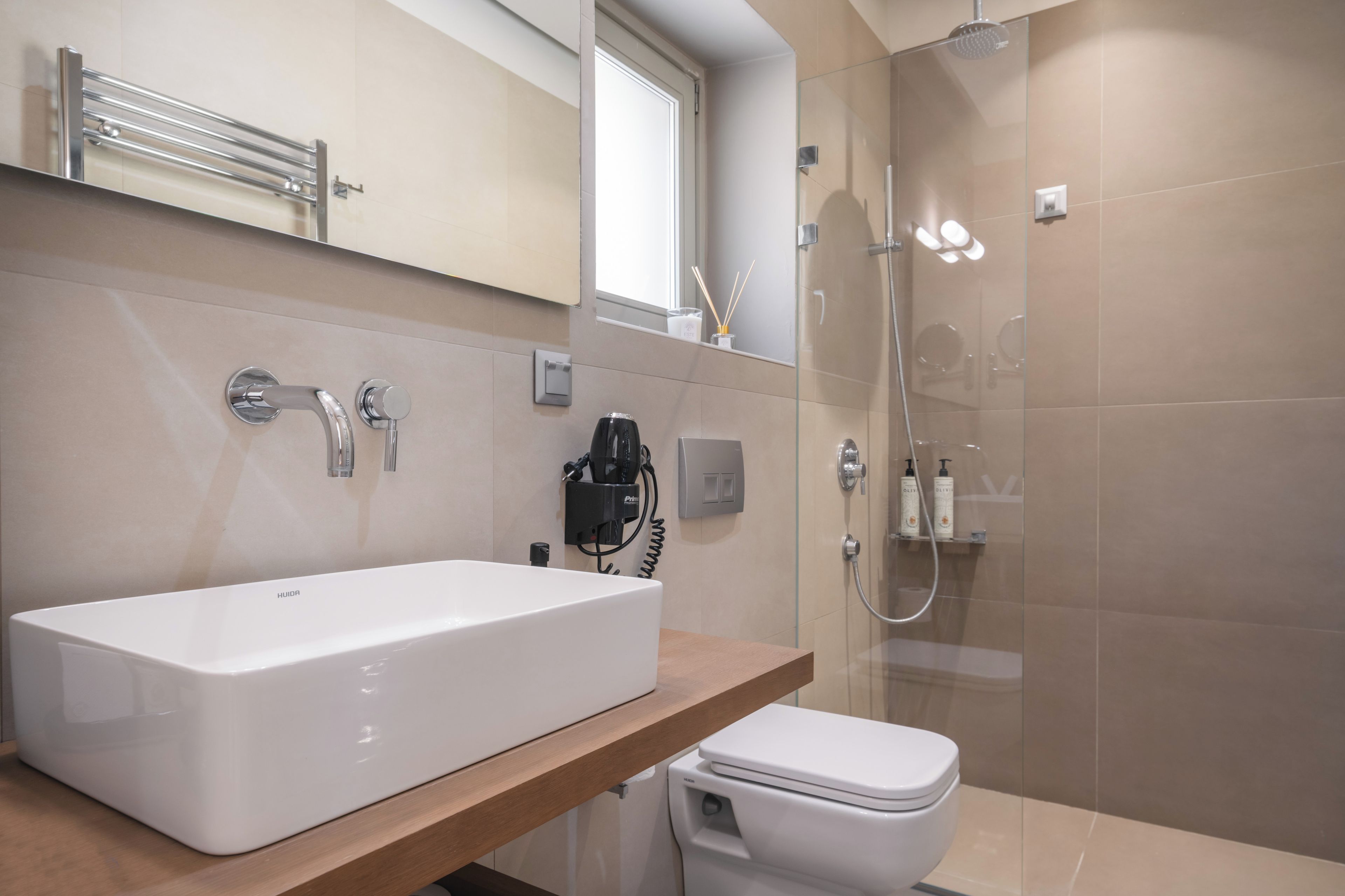 A modern bathroom with a large white bathtub, a toilet, and a glass-enclosed shower area.