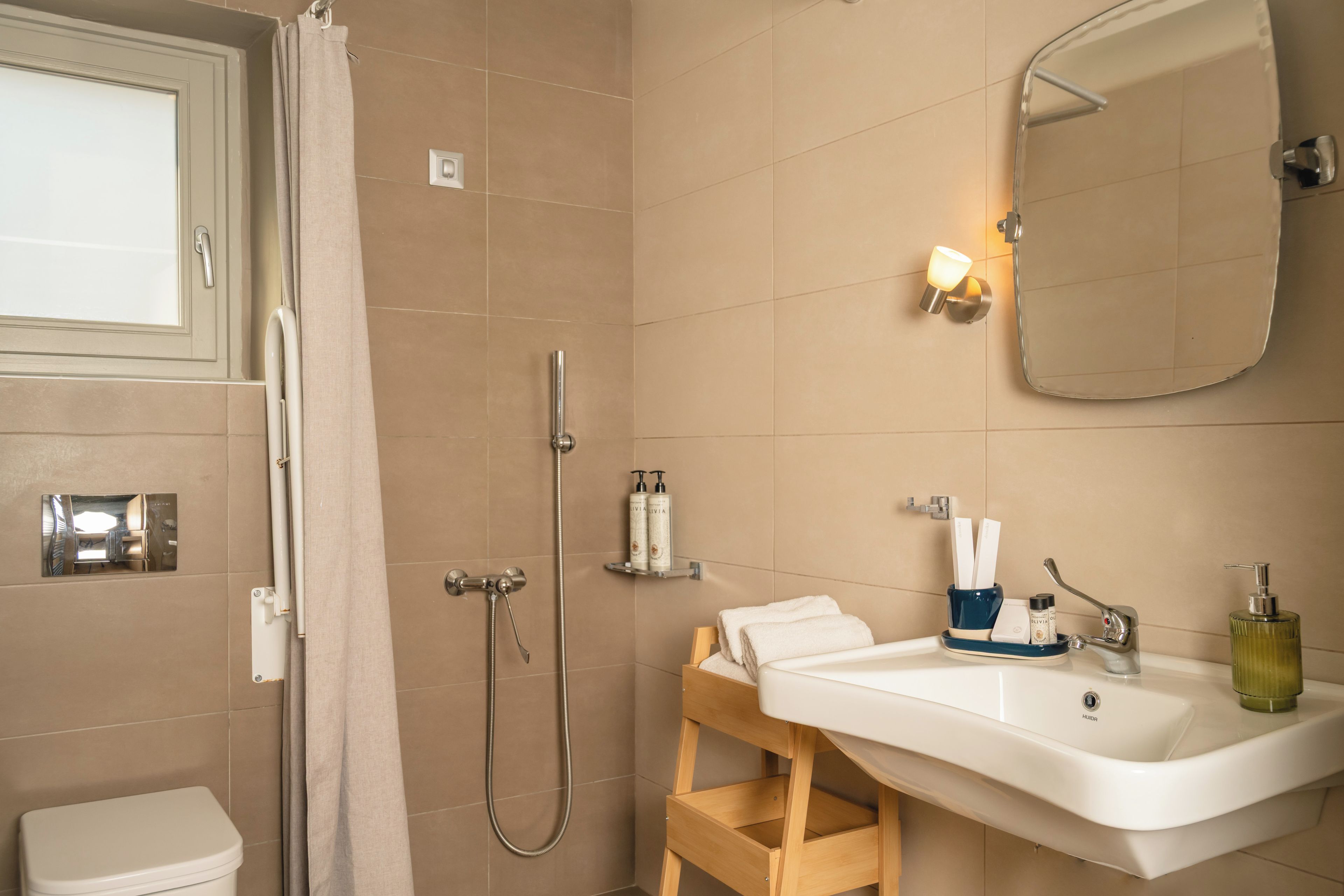A bathroom with a shower, toilet, sink, and a mirror.