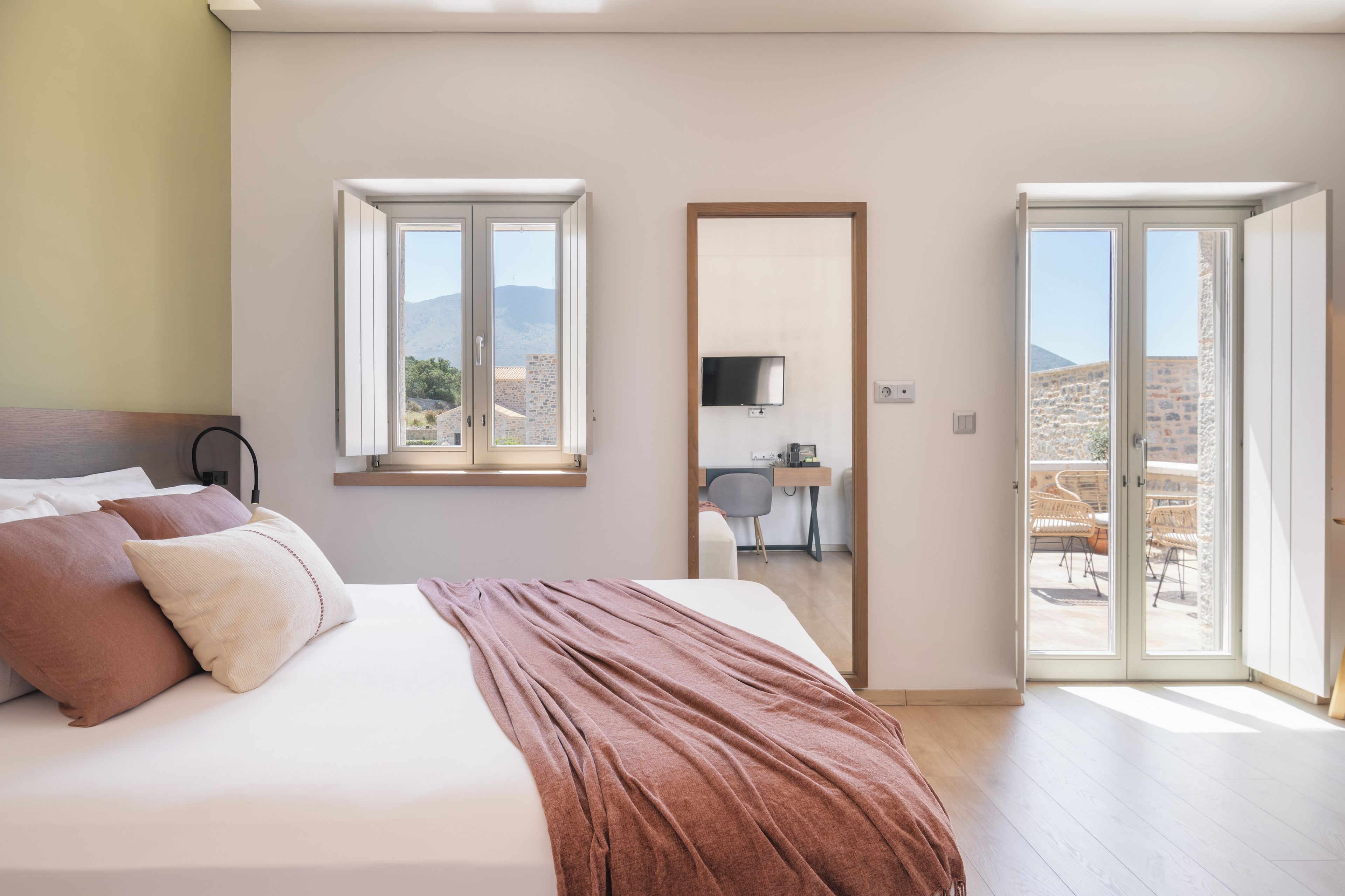 Une chambre à coucher avec un lit, un bureau et une vue sur l’extérieur.