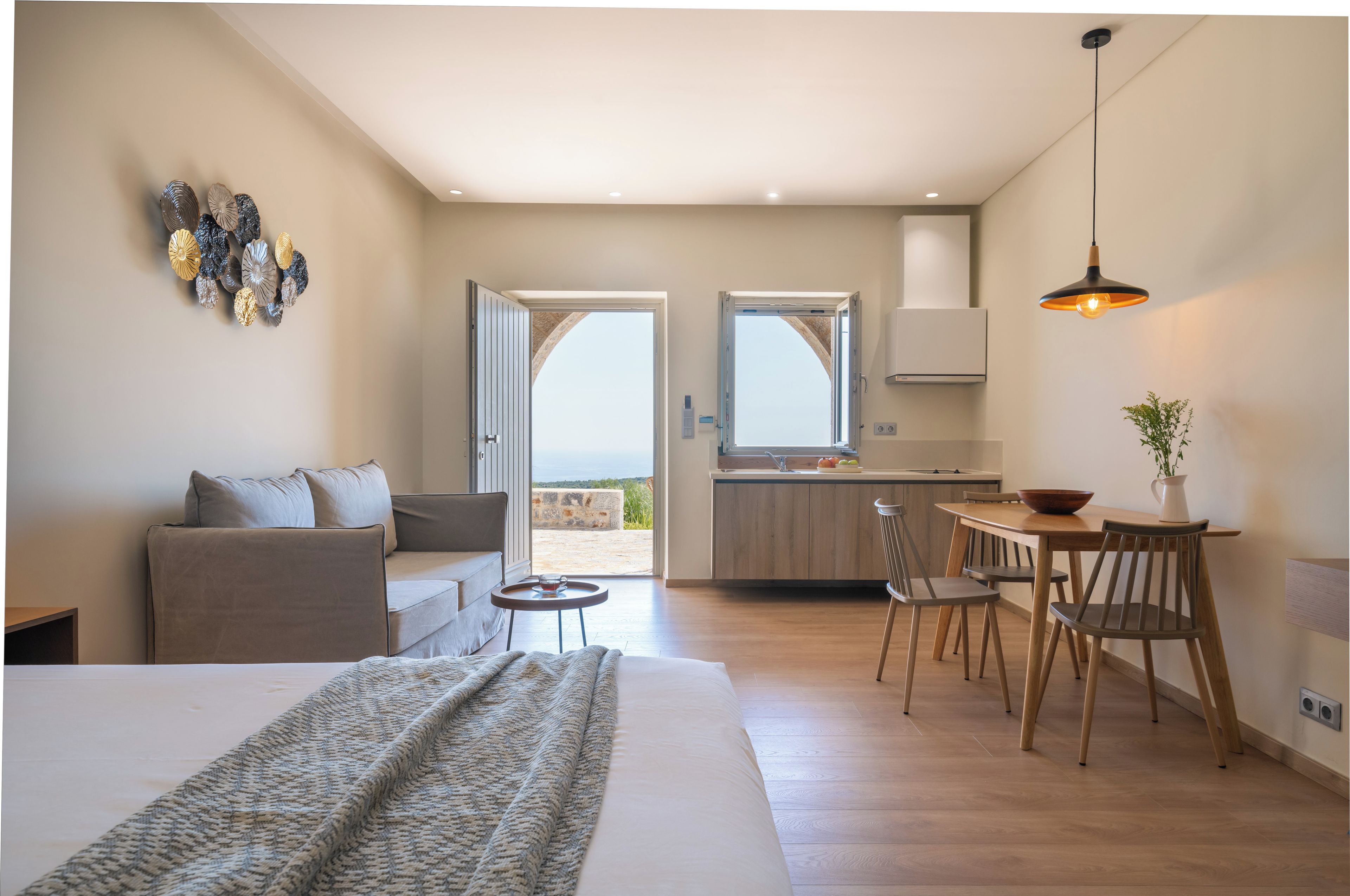 A modern interior with a bed, sofa, dining area, and kitchen.