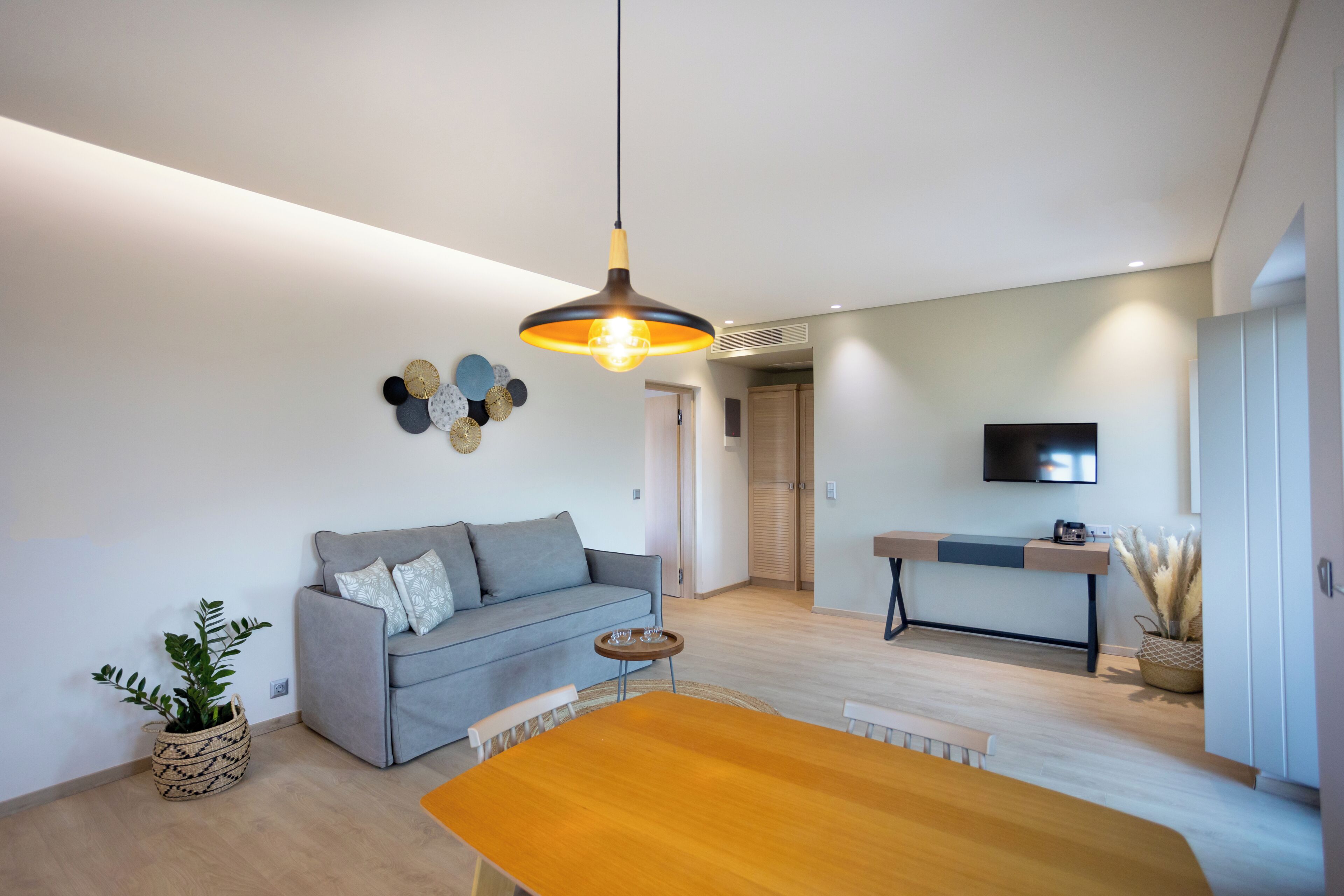 Una sala de estar moderna con sofá, mesa de comedor y lámpara colgante.