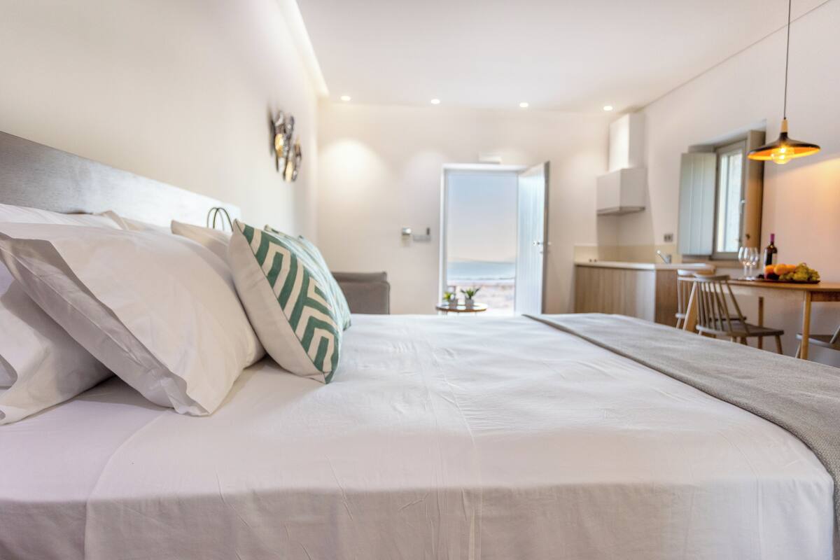 Una habitación de hotel moderna con una cama grande, un comedor y vistas al exterior.
