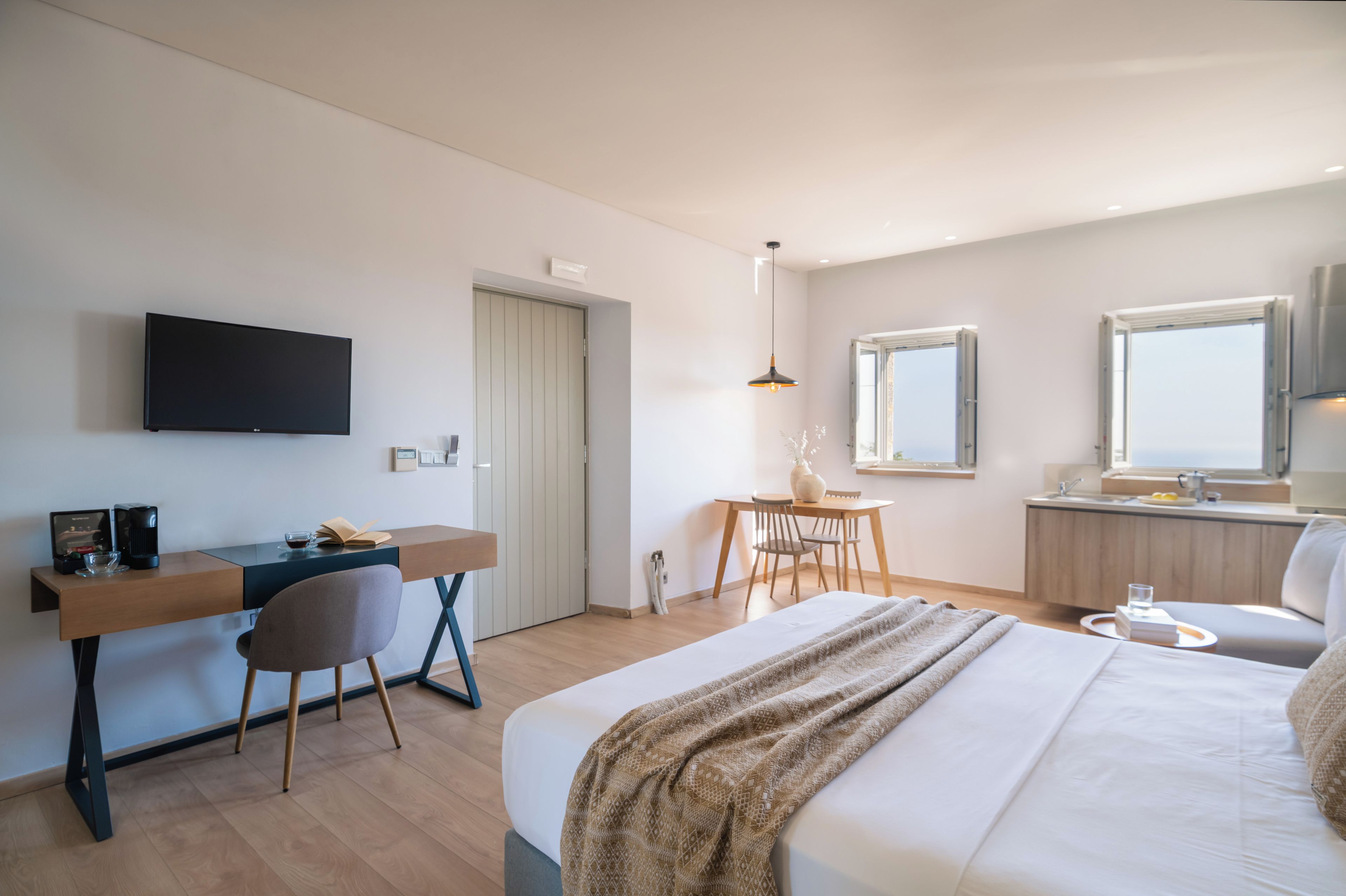 A modern hotel room with a bed, desk, chair, and a TV.