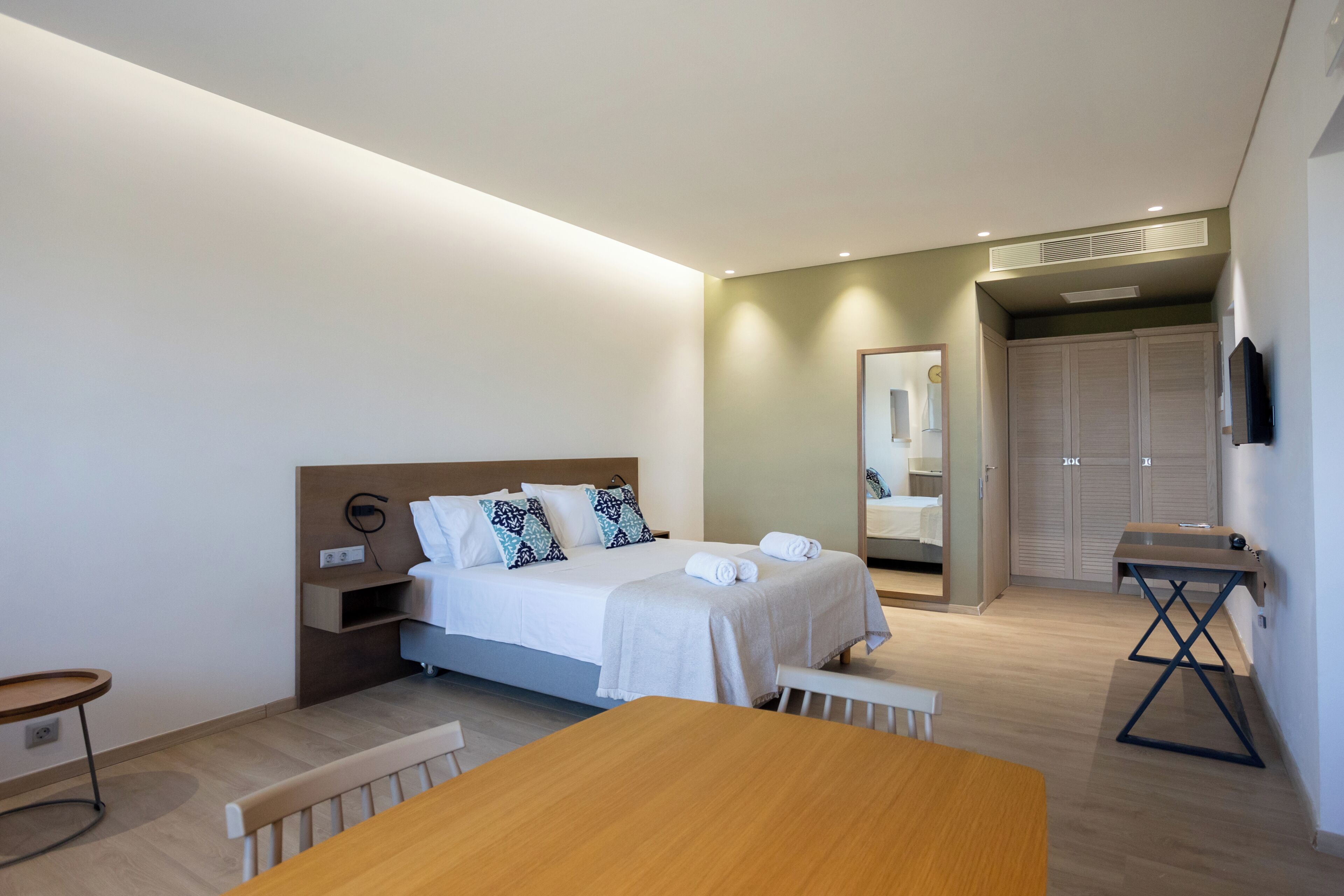 Une chambre d’hôtel moderne équipée d’un lit, d’une table de chevet et d’une petite table avec un banc.