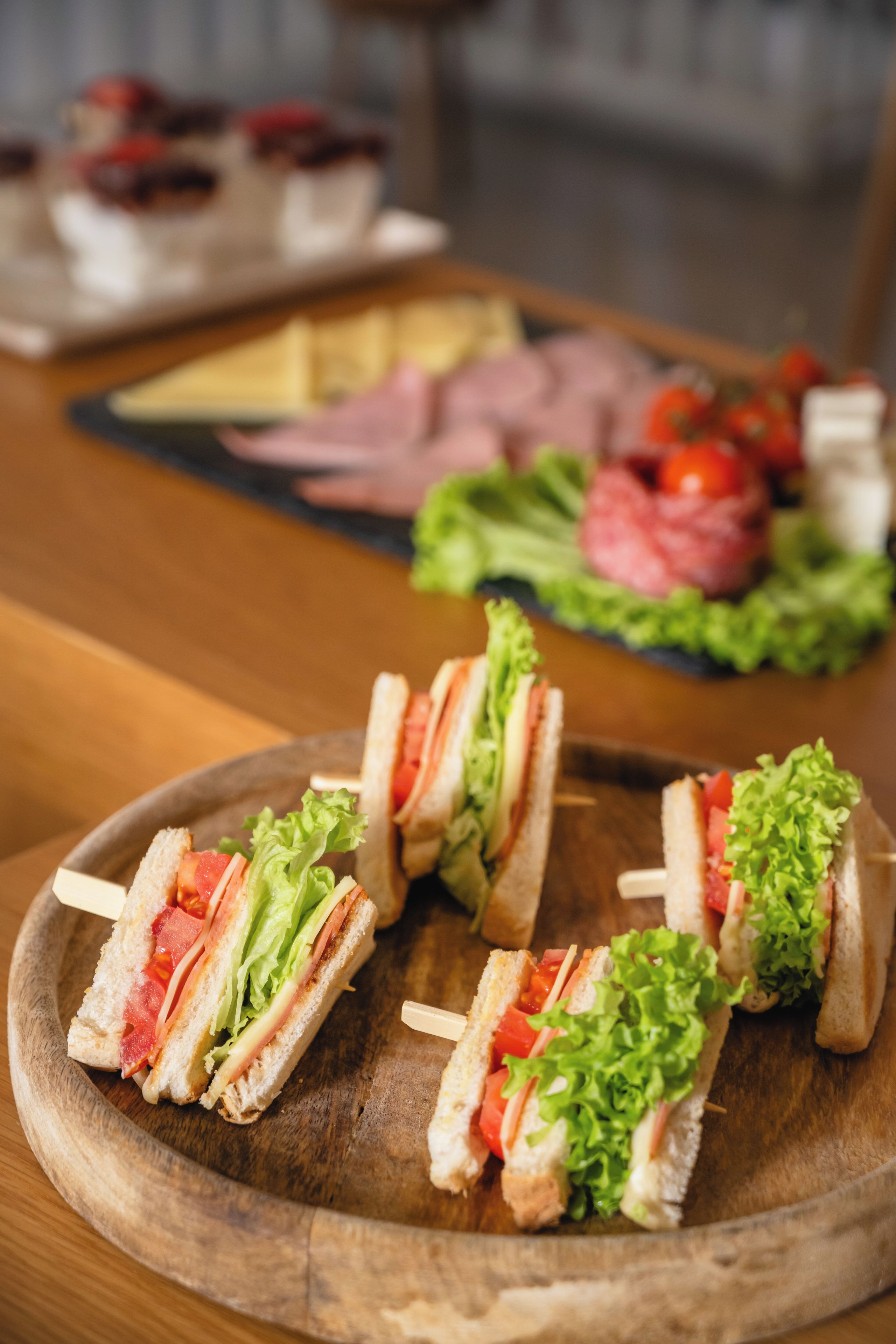 Une table en bois avec des sandwichs et un plat de viande et de légumes.