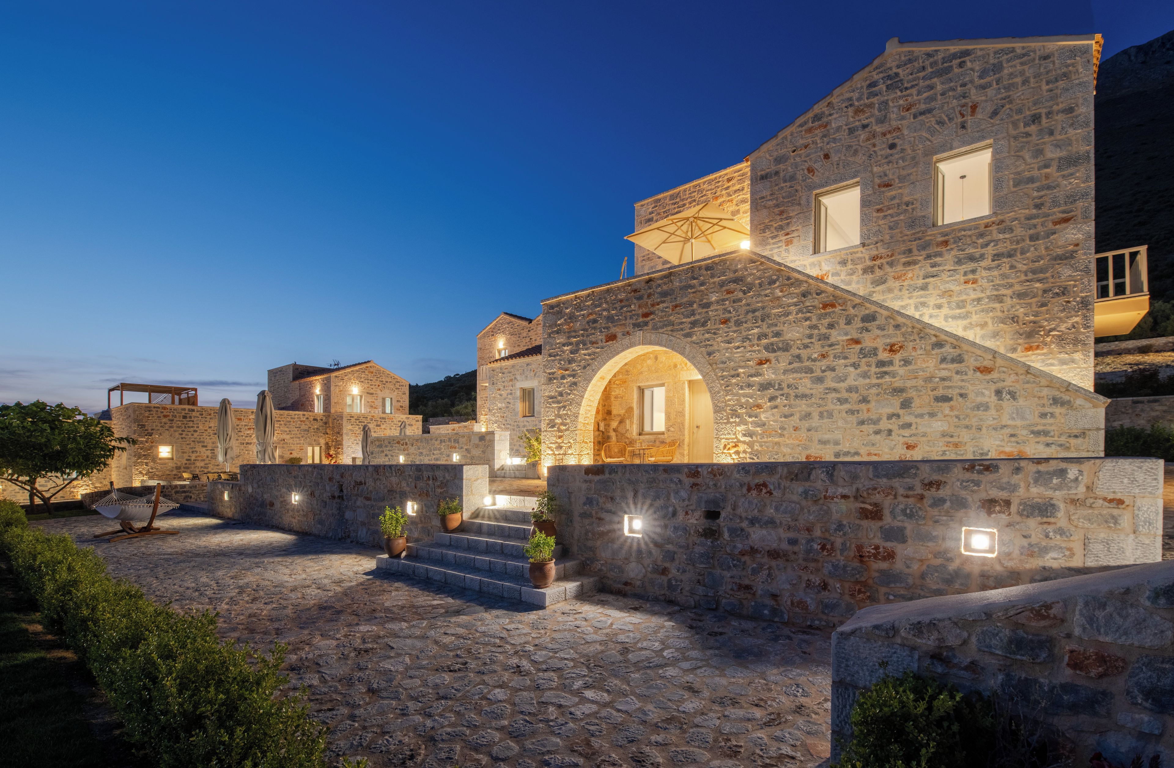 A stone building with a courtyard, steps leading to an entrance, and outdoor lighting.
