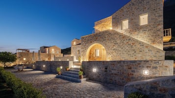A stone building with a courtyard, steps leading to an entrance, and outdoor lighting.