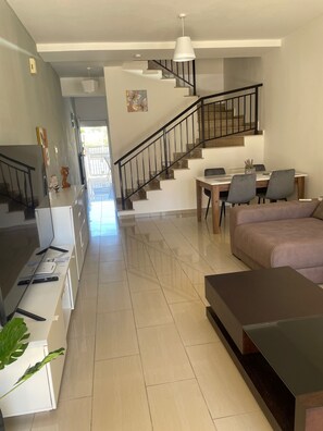 Un espacio habitable moderno con una escalera, un comedor y un sofá.