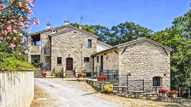 A stone building with a red door, potted plants, and a gravel driveway. - La Collina degli Ulivi by Interhome (Perugia)
