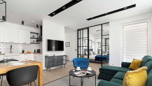 Un espacio habitable moderno con comedor, sofá, mesa de centro y televisor.