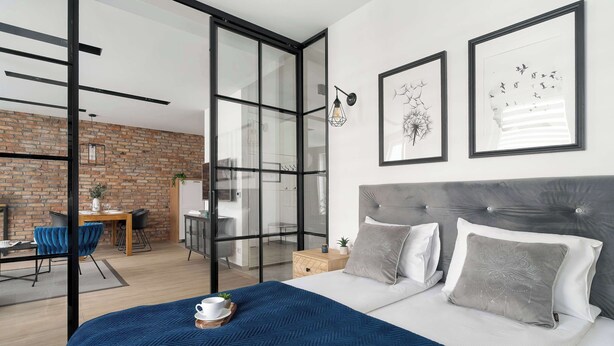 Un dormitorio moderno con una cama grande, un escritorio y un separador de vidrio.